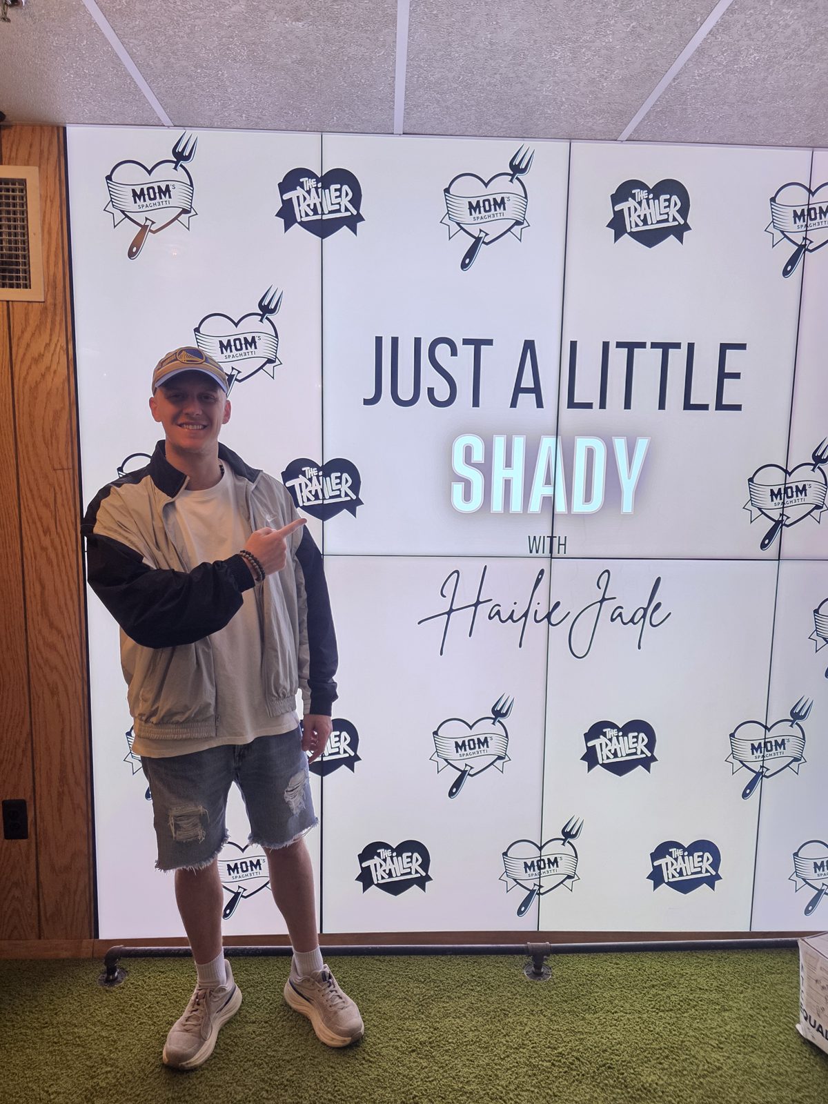 Brad Mines pointing at the Just a Little Shady with Hailie Jade wall at Mom's Spaghetti