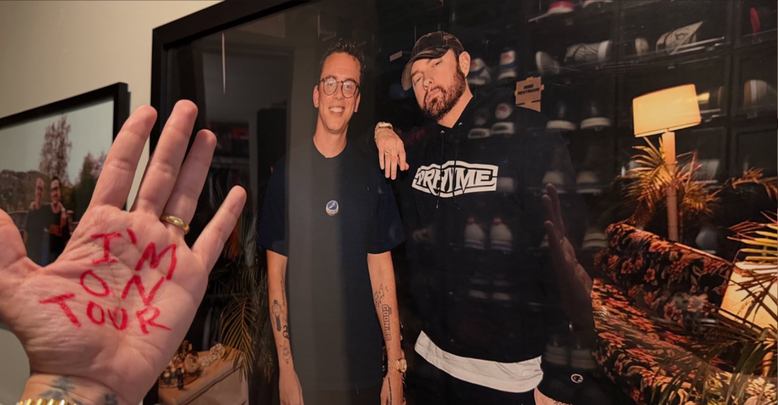Logic's hand reading I'm on tour in front of a framed photo of him and Eminem