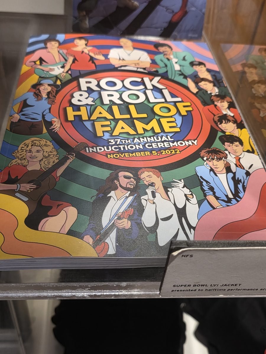 The Rock and Roll Hall of Fame 37th Annual Induction Ceremony program from November 5, 2022 in a display case at The Trailer, next to a card labelling a Super Bowl LVI jacket presented to a halftime performer
